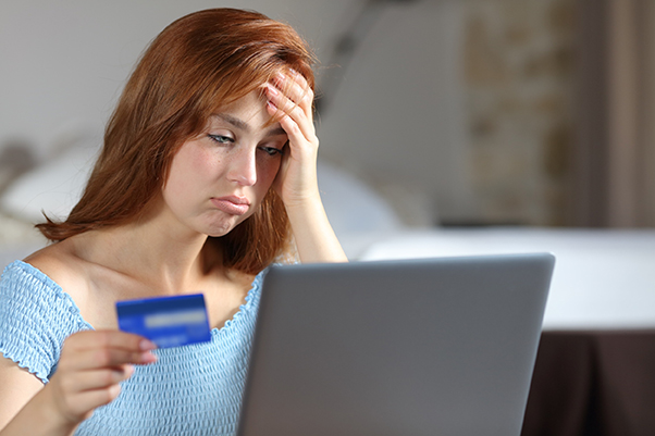 Jeune femme rousse faisant un achat sur un site e-commerce et rencontrant des problèmes pour le paiement par carte