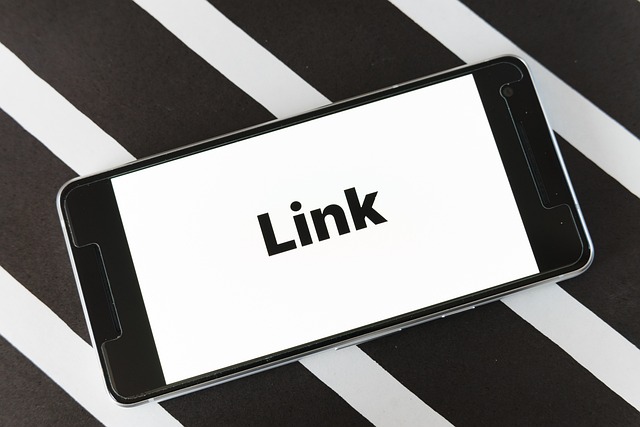 « LINKS » écrit en noir sur l’écran d’un portable, posé sur un support à rayures blanches et noires